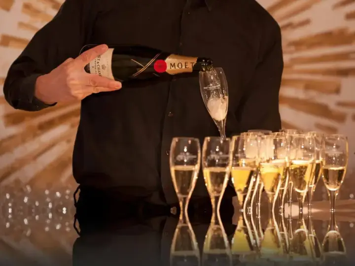 Kelner nalewa szampan Moët & Chandon do kieliszków, przygotowując się do wesela.