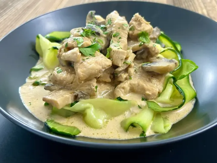 Pyszny keto obiad z kurczakiem w kremowym sosie z pieczarkami, podany z makaronem z cukinii.