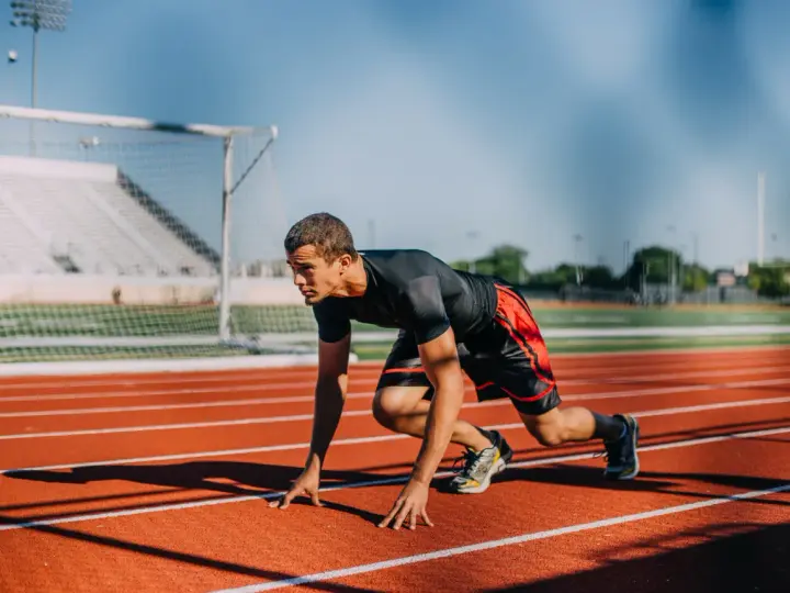Atleta en posición de salida en pista de atletismo. ¿Cuánto cobra un profesor de educación física?