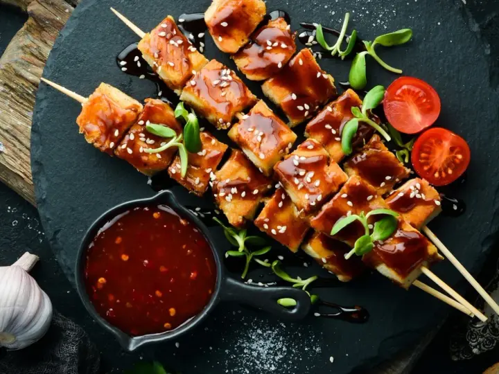 Hähnchenspieße mit glänzender Teriyaki-Sauce, Sesam und Kirschtomaten. Ein köstliches teriyaki sauce rezept zum Nachmachen.