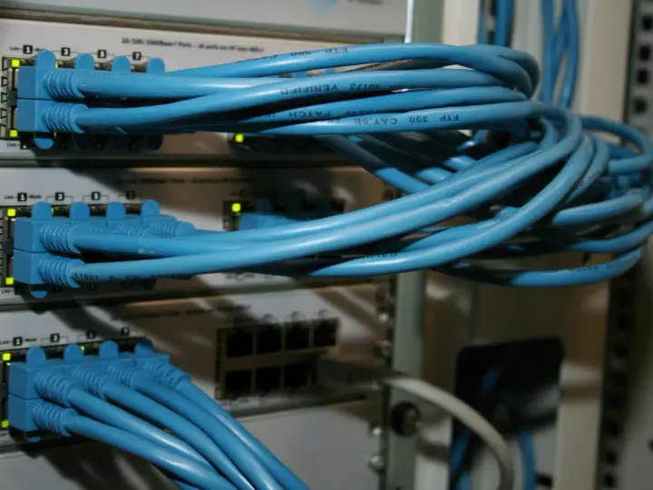 Sieć komputerowa z niebieskimi kablami Ethernet podłączonymi do przełączników. Połączenia peer to peer tworzą infrastrukturę.