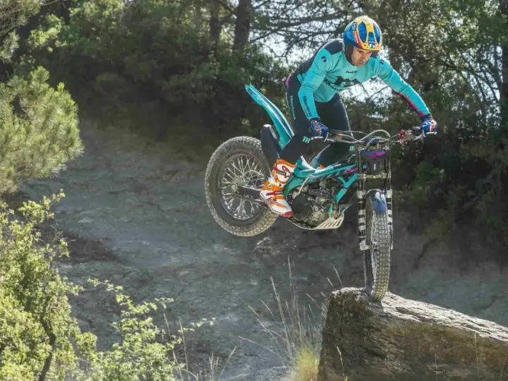 Un pilota esperto con una Honda Montesa compie un salto su un masso in un percorso fuoristrada.