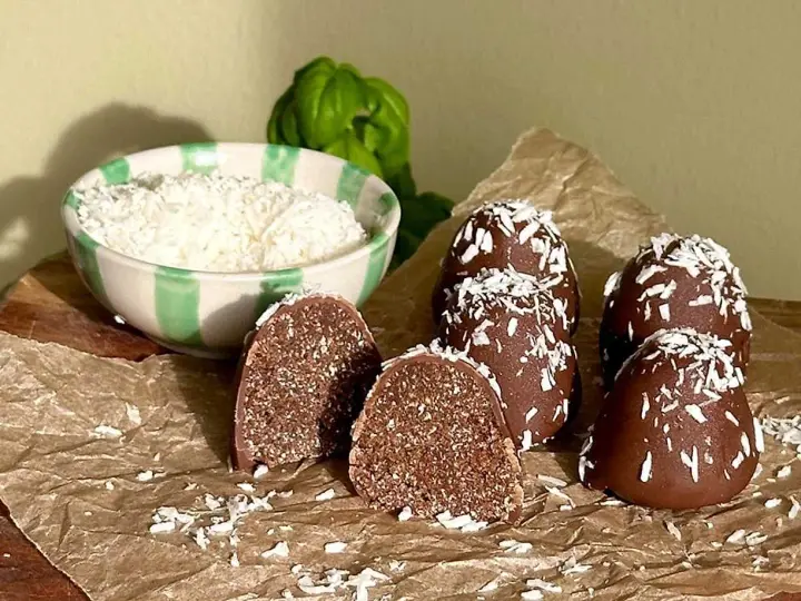 Chokladbollar recept: Mörka, kokosdränkta godsaker med en skål riven kokos i bakgrunden. Perfekt för fikat!