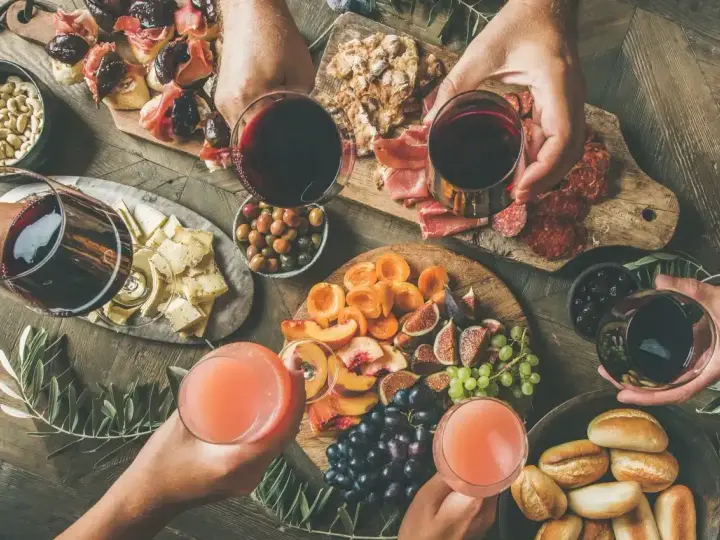 Stół z przekąskami: wędliny, sery, owoce, pieczywo i napoje.