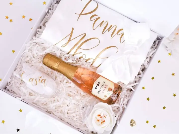 Elegancki prezent na wieczór panieński: kieliszek z imieniem, butelka prosecco i biała szarfa z napisem "Panna Młoda".