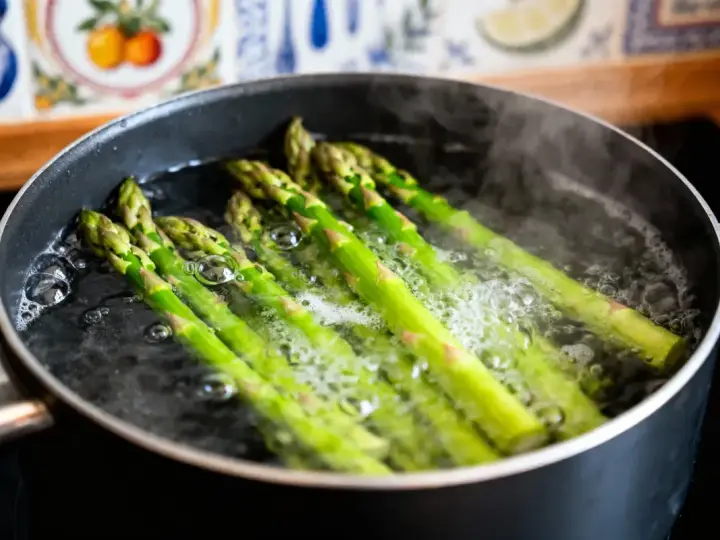 Asperges vertes bouillonnant dans une casserole, prêtes pour une recette simple et savoureuse.
