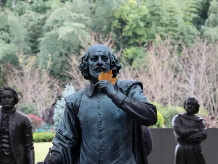 Staty av Shakespeare med ett löv framför munnen, som ett sonett exempel. Bakom syns andra statyer och träd.