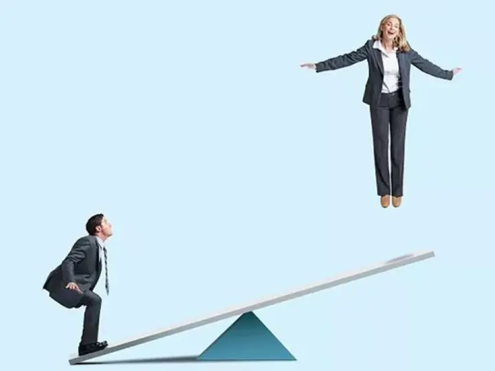 Un homme en costume sur une bascule regarde une femme en l'air. Un devoir de secours pour la faire descendre ?