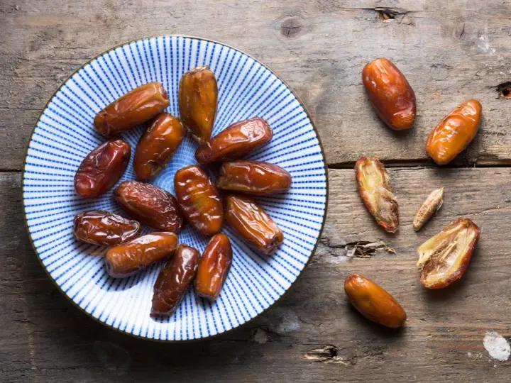 Assiette de dattes sur fond de bois. Une personne souffrant d'allergie aux dattes ne peut pas en manger.