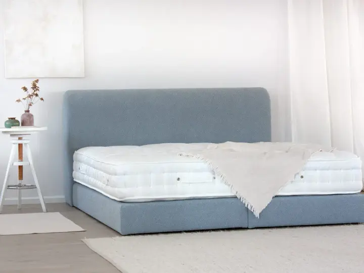 Ein Boxspringbett mit blauem Stoffbezug und weißer Matratze. So wird ein Boxspringbett geliefert: zerlegt und einfach aufzubauen.