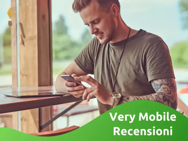 Uomo con tatuaggi guarda il suo smartphone, leggendo le very opinioni su "Very Mobile Recensioni".