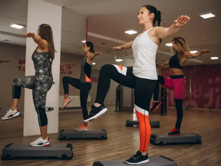 Kobiety na stepach wykonują trening aerobowy co to jest, ćwicząc równowagę i kondycję.