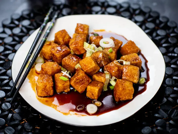 Krispiga, glaserade tofubitar med salladslök och en mörk sås. Ett läckert tofu recept som ser fantastiskt ut!