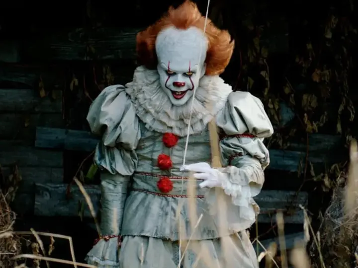 Przerażający klaun Pennywise, znany z horrorów Netflix, wychodzi z mroku.