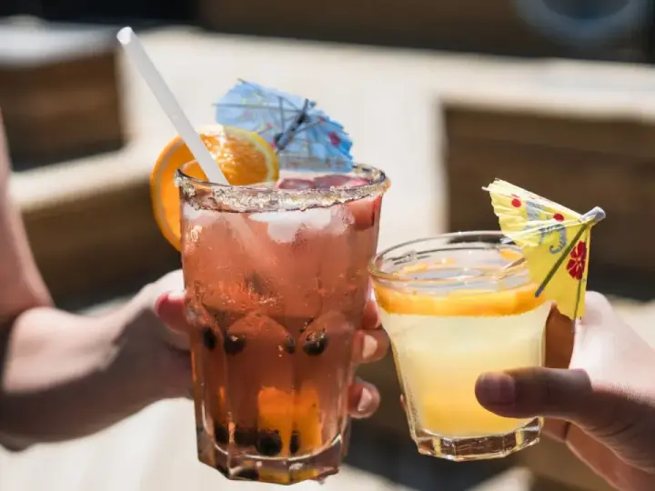 Dwa orzeźwiające drinki, jeden różowy z owocami i pomarańczą, drugi żółty z plasterkiem pomarańczy. Idealne na letnie popołudnie, może z dodatkiem białego wina.