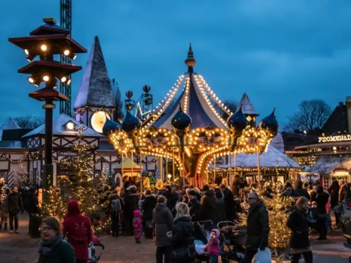 A lively Copenhagen Christmas market at dusk, with a brightly lit carousel and festive stalls. People stroll amongst decorated trees, enjoying the magical atmosphere.
