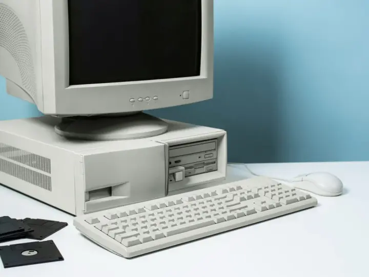 Stary komputer stacjonarny z monitorem CRT, klawiaturą, myszką i kilkoma dyskietkami.