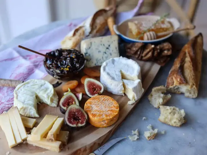 Plateau de fromages variés, dont un fromage à pâte cuite, avec figues, confiture et pain.
