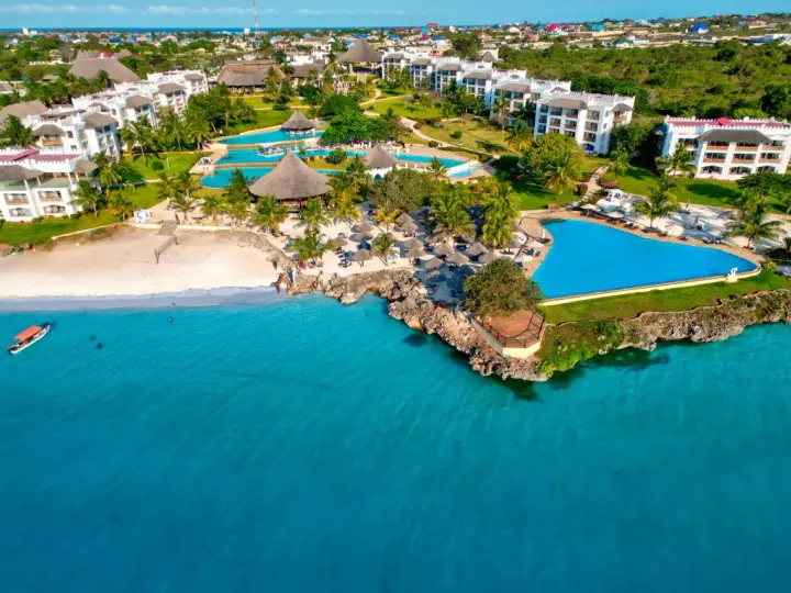 Widok z samolotu na tropikalny kurort na Zanzibarze z białymi budynkami, basenami i plażą nad turkusowym oceanem.