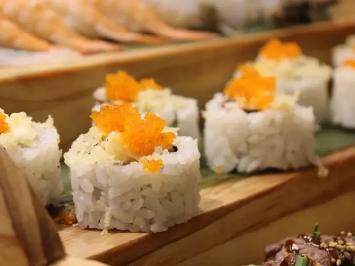 Roladki sushi z pomarańczową ikrą i chrupiącą posypką, idealne do słodkiego sosu do sushi.