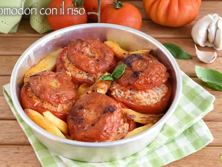 Pomodori ripieni di riso, cotti al forno con patate e basilico. Un piatto estivo saporito e colorato.