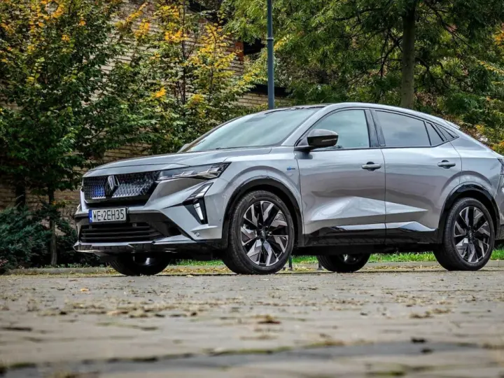 Nowy Renault Rafale, elegancki SUV coupe, prezentuje się na tle jesiennej zieleni i ceglanej ściany.