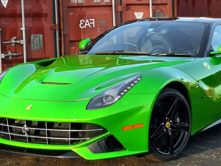Jaskrawozielone Ferrari F12 Berlinetta z czarnymi felgami, zaparkowane przed czerwonym kontenerem.