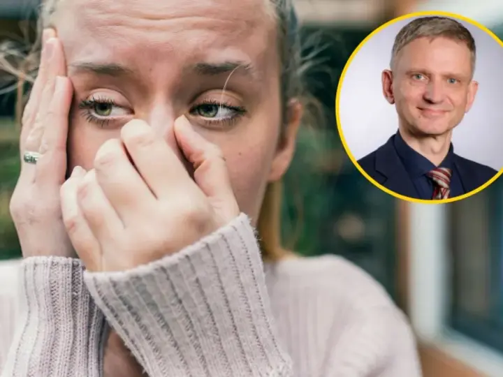 Zmartwiona kobieta z dłońmi na twarzy, jakby walczyła z amnezją. Obok niej uśmiechnięty mężczyzna w garniturze.