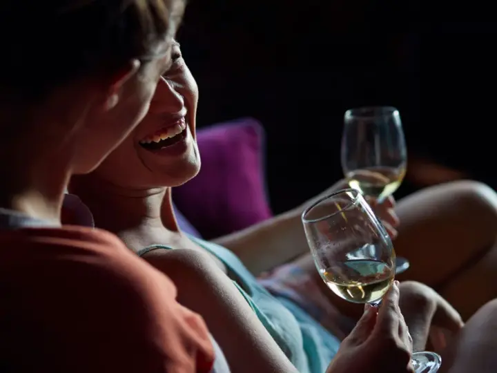 Couple partageant un verre de vin blanc, rires et complicité. L'alcool et la libido chez l'homme peuvent être liés, mais ici, c'est la joie qui prime.