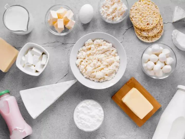 Różnorodne produkty bogate w wapń: mleko, sery, jogurt, masło, jajko i wafle ryżowe.