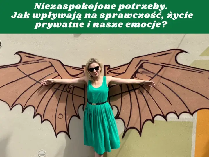 Kobieta w zielonej sukience stoi przed muralem z brązowymi skrzydłami.