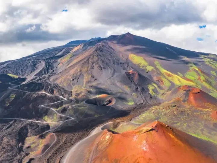 Vue aérienne de l'Etna, avec ses cratères rouges et ses pentes noires et vertes.