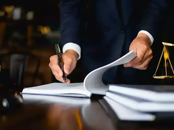 Un avocat examine des documents, une balance de la justice et un maillet sur un bureau. Il semble qu'il soit confronté à une situation où je ne peux pas payer la prestation compensatoire.