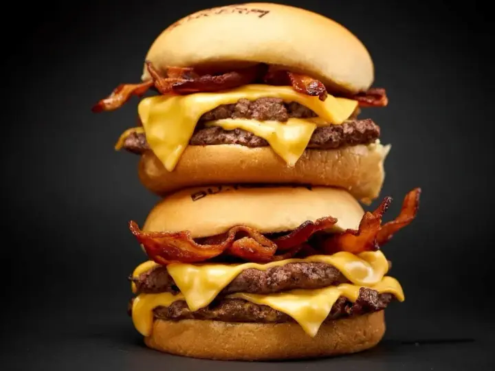 Dos hamburguesas caseras apiladas, con doble carne, queso fundido y crujiente tocino.
