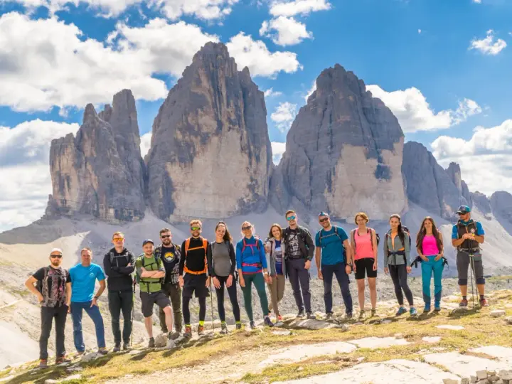 Grupa przyjaciół na tle Tre Cime di Lavaredo podczas niezapomnianego trekkingu w Dolomitach.