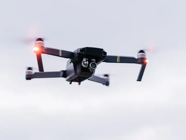 A drone hovers in the sky, its red lights blinking. Planning a trip? Be aware of Bahamas drone laws before you fly.