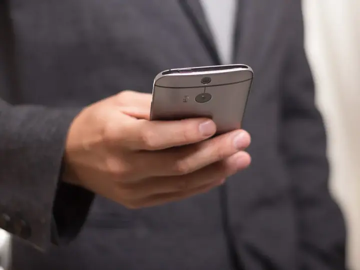 Mężczyzna w garniturze trzyma telefon, zastanawiając się, jak złożyć kondolencje przez telefon.