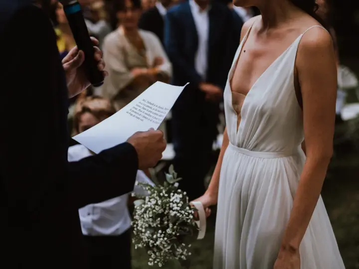 La mariée en robe blanche, bouquet à la main, écoute les vœux lors de son mariage religieux.