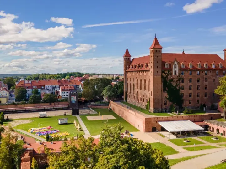 Zamek w Gniewie zaprasza na zwiedzanie. Potężna ceglana budowla z czerwonym dachem i wieżyczkami góruje nad miastem.