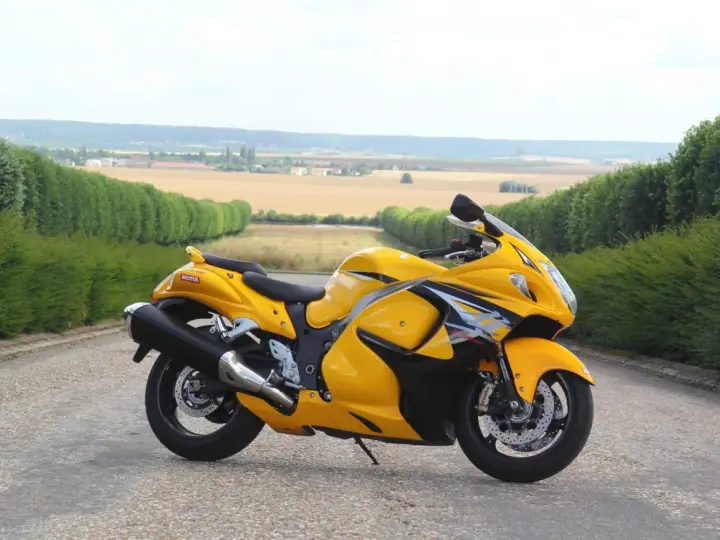 Żółty Suzuki Hayabusa na tle pól i zielonych żywopłotów. Sprawdź aktualną suzuki hayabusa cena!