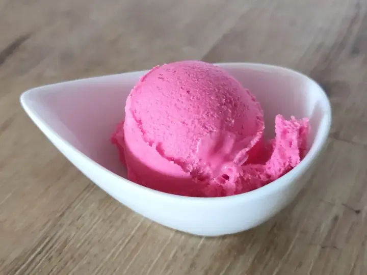 Ein Löffel leuchtend pinkes Eis in einer weißen Schale. Vielleicht ist das die Antwort auf die Frage, warum es kein Kirscheis gibt – weil dieses hier so gut ist!