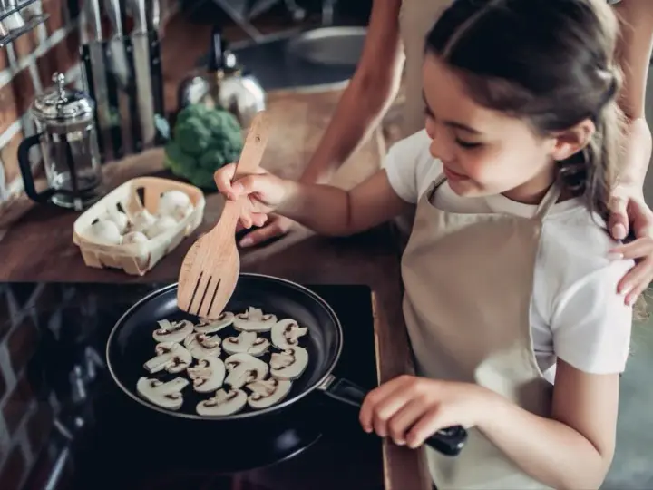 Mała kucharka smaży pieczarki na patelni. Czy dzieci mogą jeść pieczarki? Tak, to zdrowy dodatek do posiłków!