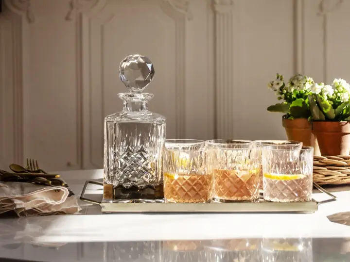 Elegancka karafka i szklanki z drinkami, idealne do serwowania bourbonu. Z czym pić bourbon? Z lodem i cytryną, jak na zdjęciu.