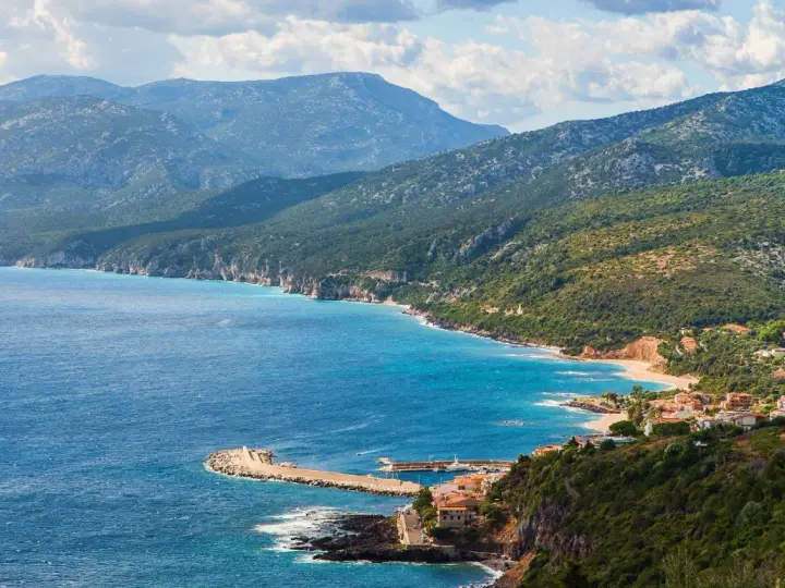 Vista panoramica di Cala Gonone, dove il blu intenso del mare incontra la costa frastagliata e le verdi montagne.