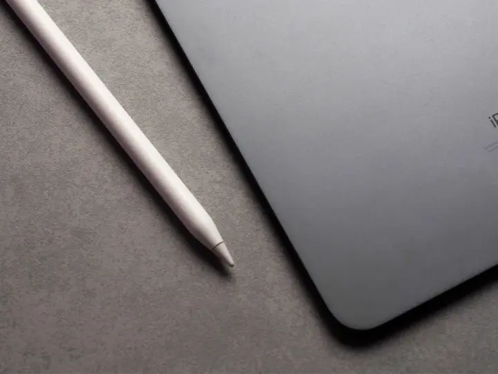 Apple Pencil liegt neben einem iPad mit drei leuchtenden Punkten.