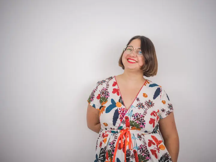 Une femme souriante porte une robe d'été colorée, un modèle inspiré d'un patron gratuit de robe Charlotte.