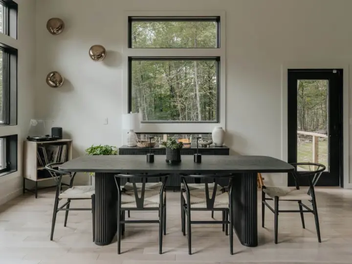 Elegante mesa negra y sillas de diseño para una perfecta decoracion comedores modernos. Ventanales con vistas al bosque.