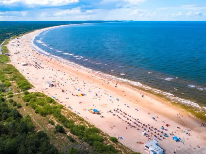 Szeroka, piaszczysta plaża z tłumem turystów, zielony las i błękitne morze – to jedne z najładniejszych plaż w Polsce.