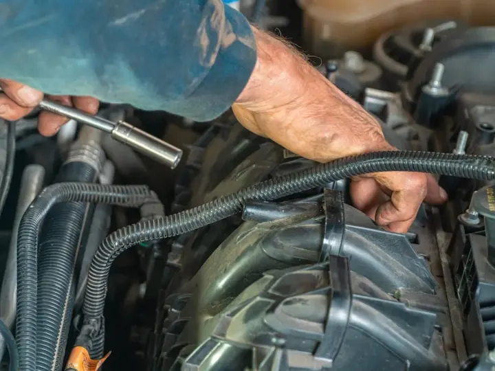 Mechanik naprawia silnik, sprawdzając uszkodzony zawór zwrotny paliwa. Objawy mogą być różne, od problemów z rozruchem po nierówną pracę silnika.