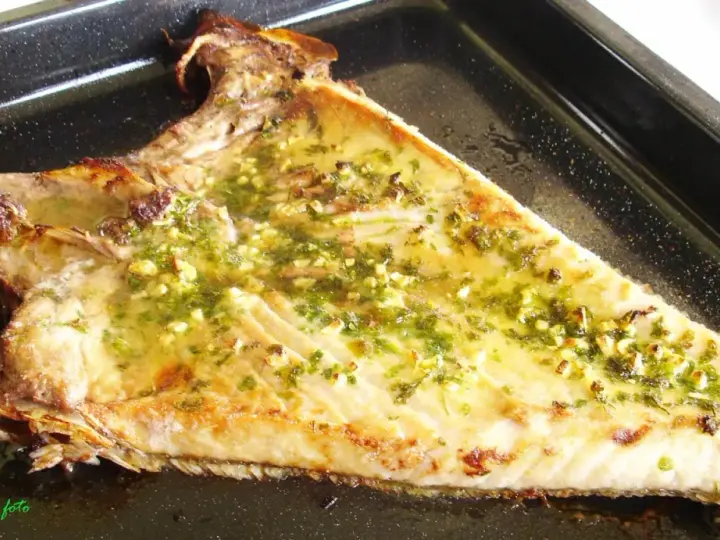 Deliciosa ventresca al horno, dorada y jugosa, con un aderezo de ajo y perejil que invita a probarla.